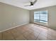Empty bedroom features neutral paint, tile floors, ceiling fan and a bright window at 9481 Highland Oak Dr # 609, Tampa, FL 33647