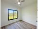 Bright bedroom with wood flooring, ceiling fan, and a large window providing ample natural light at 15561 Aldama Cir, Port Charlotte, FL 33981
