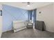 Cozy Bedroom features a blue accent wall, crib, gray rocking chair, and changing table at 17737 Canopy Pl, Bradenton, FL 34211