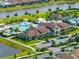 Aerial view of clubhouse with pool, tennis courts, palm trees, well manicured landscaping, and parking area at 17737 Canopy Pl, Bradenton, FL 34211
