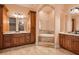 Bathroom featuring dual vanities, a soaking tub, and wood cabinetry at 2202 Sparkman Rd, Plant City, FL 33566