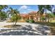 A picturesque view of an orange stucco home with a red tile roof, lush landscaping, and a circular driveway at 2202 Sparkman Rd, Plant City, FL 33566