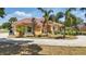 Beautiful orange stucco home featuring lush tropical landscaping, a red tile roof, and a circular driveway at 2202 Sparkman Rd, Plant City, FL 33566