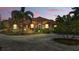 Stunning orange stucco home boasts a red tile roof, lush landscaping, and a circular driveway at twilight at 2202 Sparkman Rd, Plant City, FL 33566