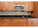 Close-up of a kitchen featuring stainless steel appliances, wood cabinetry, and a stylish tile backsplash at 11818 Gilmerton Dr, Riverview, FL 33579