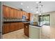 Spacious kitchen with wooden cabinets, black countertops, stainless steel appliances, and an island with pendant lighting at 11818 Gilmerton Dr, Riverview, FL 33579