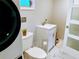 Bright bathroom featuring a toilet, sink, and a laundry area with a stackable washer and dryer at 70 Virginia Ct, Englewood, FL 34223