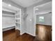Spacious walk-in closet with custom shelving and hanging racks in a light neutral color palette with dark hardwood flooring at 5213 Keene Dr, Plant City, FL 33566