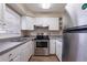 Efficient kitchen featuring white cabinets, stainless steel appliances, and wood-style flooring at 1409 N Garden Ave, Clearwater, FL 33755
