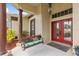 Inviting front porch with red double doors, a hanging pineapple light fixture, and a cushioned wooden porch swing at 2818 Mossy Timber Trl, Valrico, FL 33596