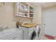 Functional laundry room with front-loading washer and dryer, complemented by a butcher block countertop and upper cabinet storage at 2818 Mossy Timber Trl, Valrico, FL 33596