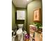 Cozy bathroom with green walls, white cabinets, artwork, and mobility assistance at 30442 Lettingwell Cir, Wesley Chapel, FL 33543