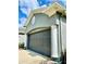 Attached two-car garage with gray door, columns and manicured landscaping at 30442 Lettingwell Cir, Wesley Chapel, FL 33543