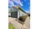 Attached two-car garage with a gray door and manicured landscaping at 30442 Lettingwell Cir, Wesley Chapel, FL 33543