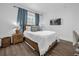 A cozy bedroom featuring a large bed, hardwood floors, and a window with blue curtains providing natural light at 1238 E Kennedy Blvd # 802, Tampa, FL 33602