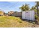 Residential backyard featuring a storage shed, wooden fence, and partial views of nearby homes and palm trees at 15406 2Nd E St, Madeira Beach, FL 33708