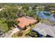 Aerial shot of a home with a red tile roof nestled by a serene lake and lush greenery at 8202 Shadow Pine Way, Sarasota, FL 34238