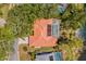 Aerial view of a terra cotta roof with solar panels, screened pool, and lush landscaping near a lake at 8202 Shadow Pine Way, Sarasota, FL 34238