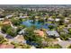 Panoramic aerial view of a residential area featuring a lake, surrounded by homes and dense trees at 8202 Shadow Pine Way, Sarasota, FL 34238