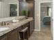 Main bathroom with dual sinks, granite countertops, dark wood cabinetry, and an open doorway to the bedroom at 6179 Notre Dame Ter, North Port, FL 34291