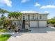 Charming two-story home with a well-maintained driveway, stairs to the front door, and tropical landscaping at 24145 Blackbeard Blvd, Punta Gorda, FL 33955
