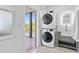 Modern laundry room featuring a stacked washer and dryer, integrated sink, and door to the outside at 24145 Blackbeard Blvd, Punta Gorda, FL 33955