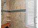 Modern shower with tan tile, glass accents, a shower seat, and shower caddy shelves, next to a louvered window at 24145 Blackbeard Blvd, Punta Gorda, FL 33955