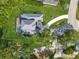 Aerial view of a home featuring a pool, lush landscaping, and circular driveway at 3008 Sutton Woods Dr, Plant City, FL 33566