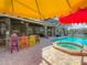 Backyard features an outdoor kitchen, a sparkling pool, and colorful barstools and umbrellas at 3008 Sutton Woods Dr, Plant City, FL 33566