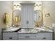 Bathroom featuring double sinks, granite countertops, decorative mirrors, and stylish lighting fixtures at 3008 Sutton Woods Dr, Plant City, FL 33566