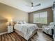 Cozy bedroom features a ceiling fan, window, and a comfortable bed with decorative pillows and wood floors at 3008 Sutton Woods Dr, Plant City, FL 33566