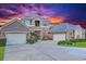 Charming home with two-car garage, a well-manicured lawn, and a sunset background at 3008 Sutton Woods Dr, Plant City, FL 33566