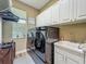 Modern laundry room with front loading washer and dryer, sink, and white cabinets with a large window at 3008 Sutton Woods Dr, Plant City, FL 33566