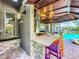 Outdoor kitchen featuring stone counters, colorful barstools, and a view of the pool and patio at 3008 Sutton Woods Dr, Plant City, FL 33566
