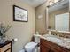 Elegant powder room featuring granite counters, wood vanity, and decorative mirror at 3008 Sutton Woods Dr, Plant City, FL 33566