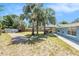 Wide shot of backyard featuring a patio, grass, palm trees, sheds, and a wooden fence at 6801 16Th N St, St Petersburg, FL 33702