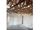Interior view of a room with exposed ceiling beams, bare walls, a door, and damaged flooring at 3360 Peace River Dr, Punta Gorda, FL 33983