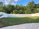 Large grassy backyard surrounded by a pristine white fence for privacy and security at 30643 Tremont Dr, Wesley Chapel, FL 33543