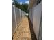 Narrow side yard with stone pavers and pea gravel between white fence and the home's exterior wall at 30643 Tremont Dr, Wesley Chapel, FL 33543