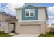 Two-story home featuring a two-car garage, covered porch and blue and tan color scheme at 34327 Verbena St, Wesley Chapel, FL 33545