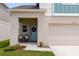 Close up of the front of the home featuring a blue door, covered porch, and two-car garage at 34327 Verbena St, Wesley Chapel, FL 33545
