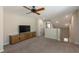 Open-concept living room featuring a ceiling fan, TV console, and neutral carpet at 34327 Verbena St, Wesley Chapel, FL 33545