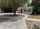 Front exterior features a yard with tree and ample driveway at 4617 John Bell Jr Dr, Tampa, FL 33610