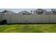 A view of the backyard featuring a well-maintained lawn and a white vinyl privacy fence with a gate at 6438 Milestone Loop, Palmetto, FL 34221