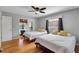 Well-lit bedroom showcasing two beds, ceiling fan, hardwood floors, and light gray walls at 9503 Alice Ln, Riverview, FL 33578