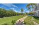 Backyard with brick paver walkway and lush landscaping with mature palm trees at 112 Osprey Point Dr, Osprey, FL 34229
