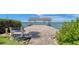 Scenic view of a covered dock with benches, accessible via a stone pathway and set against a beautiful waterfront backdrop at 112 Osprey Point Dr, Osprey, FL 34229