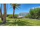 Beautiful waterfront home featuring a covered dock surrounded by lush landscaping and mature palm trees on a sunny day at 112 Osprey Point Dr, Osprey, FL 34229