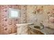 Charming powder room with floral wallpaper, custom vanity, and decorative lighting at 112 Osprey Point Dr, Osprey, FL 34229