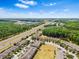 An aerial view of a community surrounded by lush greenery, highways, and commercial areas under a bright sky at 2943 Willowleaf Ln, Wesley Chapel, FL 33544